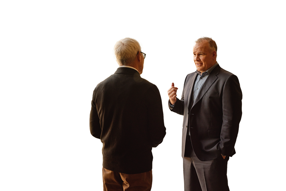 two business men standing and talking in office hallway with glass windows, angled bracket animation floating to right