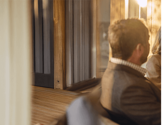 side and back view of man seated on couch meeting with an unseen financial advisor