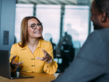 seated financial advisor in front of laptop talking with client